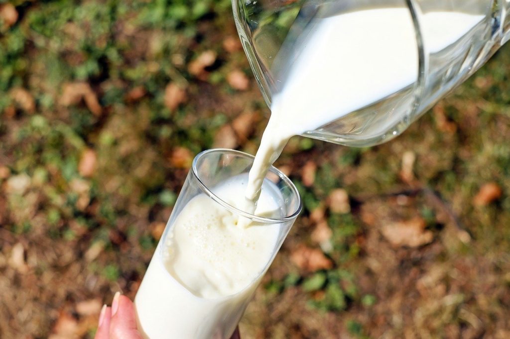 Milch wird von einer Glaskaraffe in ein Glas gegossen