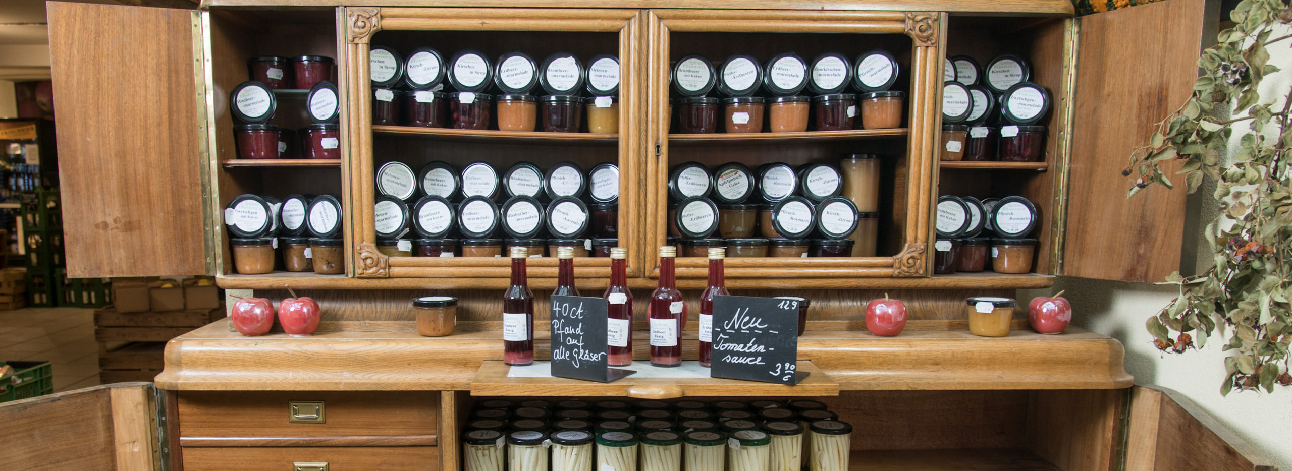 Holzschrank mit hausgemachten Produkten wie Marmeladen Spargel oder Tomatensauce