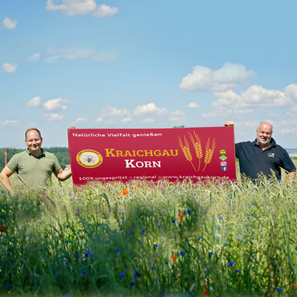 Mitglieder von KraichgauKorn im Feld mit Werbeschild