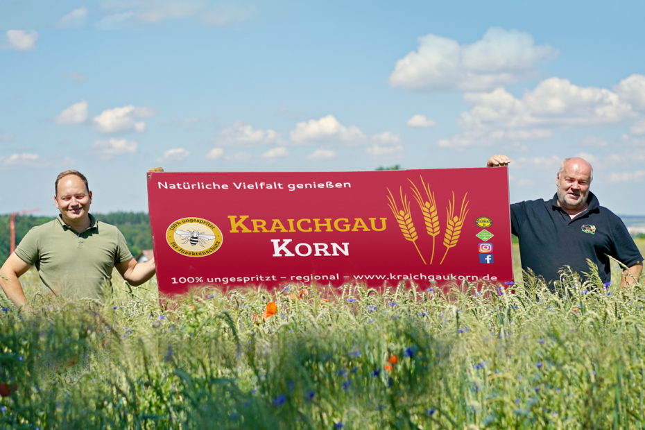 Mitglieder von KraichgauKorn im Feld mit Werbeschild